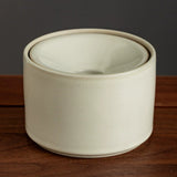 Plain cream ceramic ashtray on wooden surface