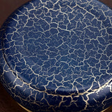 Close-up of a blue brass ashtray bottom with a cracked glaze pattern