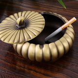 Brass ashtray with lid partially open cigarette rest groove detail