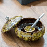 Yellow Glaze ceramic ashtray with lid and cigarette rest on wooden table
