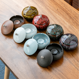 Collection of ceramic ashtrays with lids on a wooden table