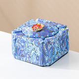 Blue swirl covered ceramic ashtray with red enamel decorative knob and cigarette rests