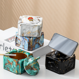Covered ceramic ashtray with ram head knob used as a phone support on tabletop