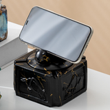 Black gold covered ceramic ashtray with ram head knob supporting a phone for light tabletop viewing