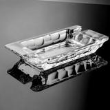 Clear crystal glass cigar ashtray with faceted rectangular bowl on black background
