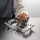 Crystal glass cigar ashtray with cigar resting on groove