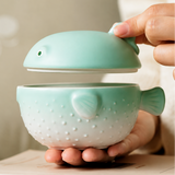 Hand lifting the lid from green ceramic pufferfish ashtray