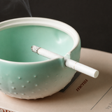 Green ceramic ashtray with lid open and cigarette rest