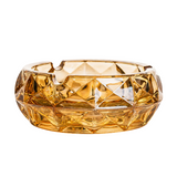 Amber faceted glass ashtray for cigarettes on white background