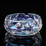 Iridescent faceted glass ashtray on reflective black surface