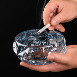 Clear blue glass ashtray held in hands with cigarette