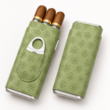 Open sage green leather cigar case holding three cigars beside closed case