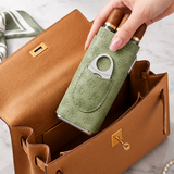 Hand placing sage green three cigar leather case into tan handbag