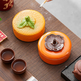 Orange and persimmon ceramic ashtrays with lids on tea table
