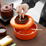 Persimmon ceramic ashtray with lid being lifted during use