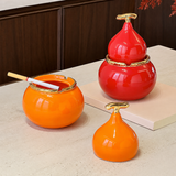 Orange and red gourd-shaped ceramic ashtrays with lids styled on tabletop