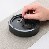 Heavyweight stone ashtray being used to extinguish cigarette ash