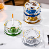 Stacked blue and gold glass ashtrays with cigarette rest grooves and crystal-style iceberg design