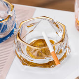 Gold iceberg glass ashtray in use with cigarette, gold rim, and luxury crystal-style design