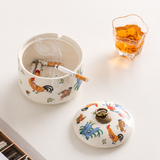 Rooster pattern ceramic ashtray with lid, cigarette rests, and drink on white tabletop