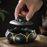 Hand lifting the removable lid from a teal lotus flower resin ashtray