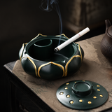 Open teal lotus flower resin ashtray holding a cigarette with the lid beside it