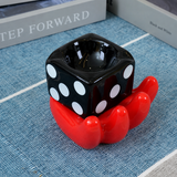 Black dice ceramic ashtray with red hand holder on blue fabric