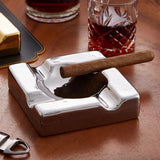 Silver square ceramic cigar ashtray with cigar and whiskey glass on wooden table