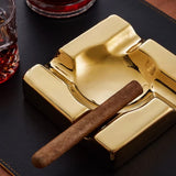 Close-up of gold electroplated ceramic cigar ashtray with cigar on dark background