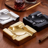 Gold and black square ceramic cigar ashtrays on wooden table with whiskey glasses