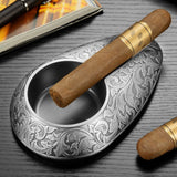 Gunmetal silver engraved cigar ashtray with cigar resting on top