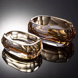 Two luxury faceted crystal glass ashtrays in amber tones on reflective surface