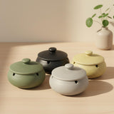 Matte ceramic ashtrays with lids in sage green charcoal black sand beige and stone gray on a light wood table minimalist Japandi style