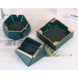 Three emerald green ceramic ashtrays with gold accents and grooves to rest cigarettes