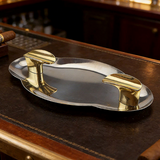 Silver and gold stainless steel cigar ashtray with dual cigar rests on leather bar counter