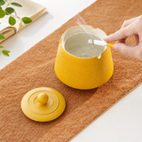 Open mustard yellow ceramic ashtray with cigarette and lid placed beside it