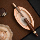 Oval ceramic cigar ashtray with cigars and matching teaware on a brown table mat