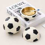 Soccer ball covered ashtray with gold metal tray displayed on decorative book