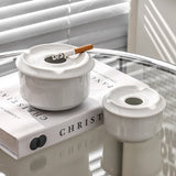 White ceramic ashtrays with lid on reflective tabletop
