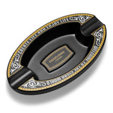 Black oval resin cigar ashtray with decorative border on white background