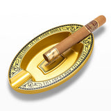 Gold oval resin cigar ashtray with cigar on white background