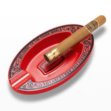 Red oval resin cigar ashtray with cigar on white background