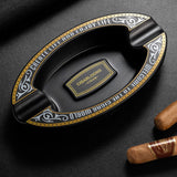 Black decorative resin cigar ashtray on dark surface with cigar
