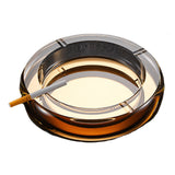 Gold round crystal glass ashtray with cigarette on white background
