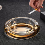 Gold round crystal glass ashtray with cigarette on dark surface