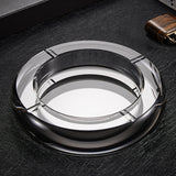 Smoked gray round crystal glass ashtray on dark surface