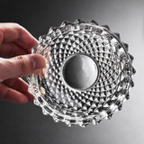 Hand holding a textured clear glass ashtray on a dark surface