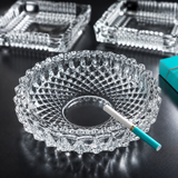 Clear glass ashtray with a cigarette on a dark surface