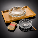 Two crystal ashtrays on a wooden tray with a cigarette and lighter.
