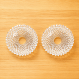Two clear glass ashtrays with a unique diamond design on a wooden surface.